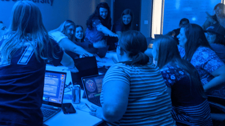 Teachers work together during an engaging mission where they are putting their hands together in a united way as they successfully overcome a challenge.