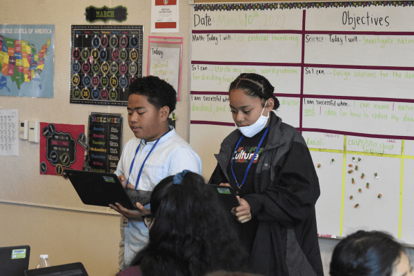 Student team speaking and reading in front of their class.