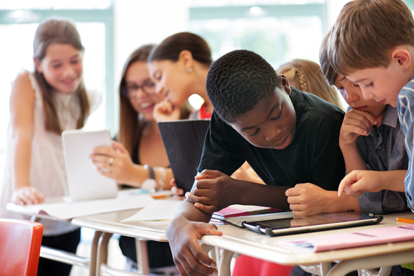 Middle school students collaboratively working on a real-world project in teams in a classroom setting.